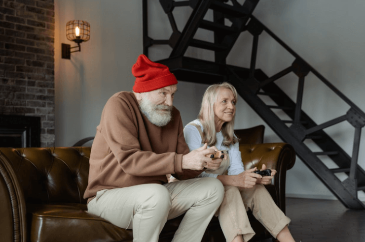 Ein Mann und eine Frau über 50 Jahre alt sitzen auf dem Sofa und spielen Videospiele